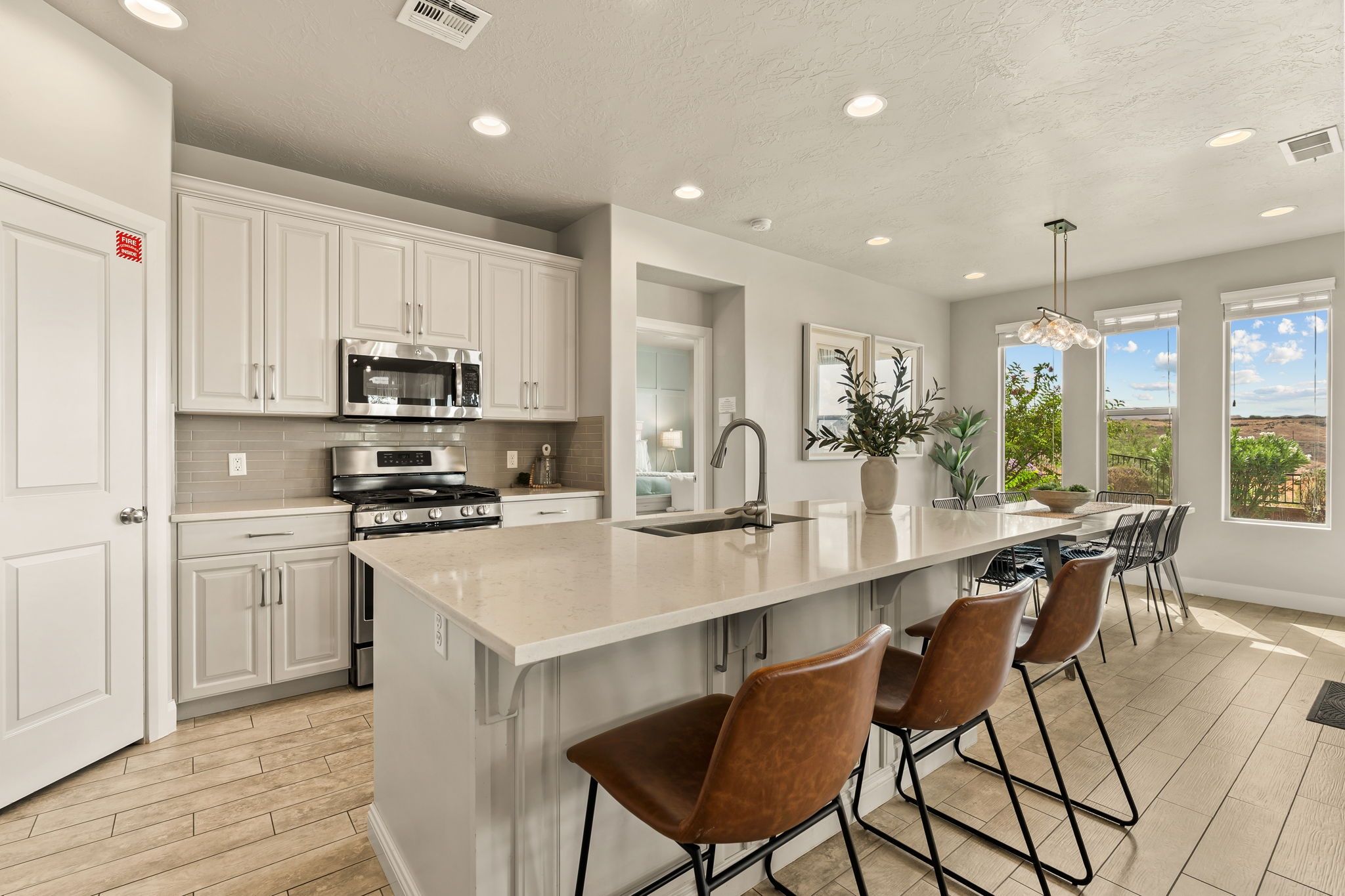 A modern kitchen with white cabinetry, stainless steel appliances, and a large island with bar stools.