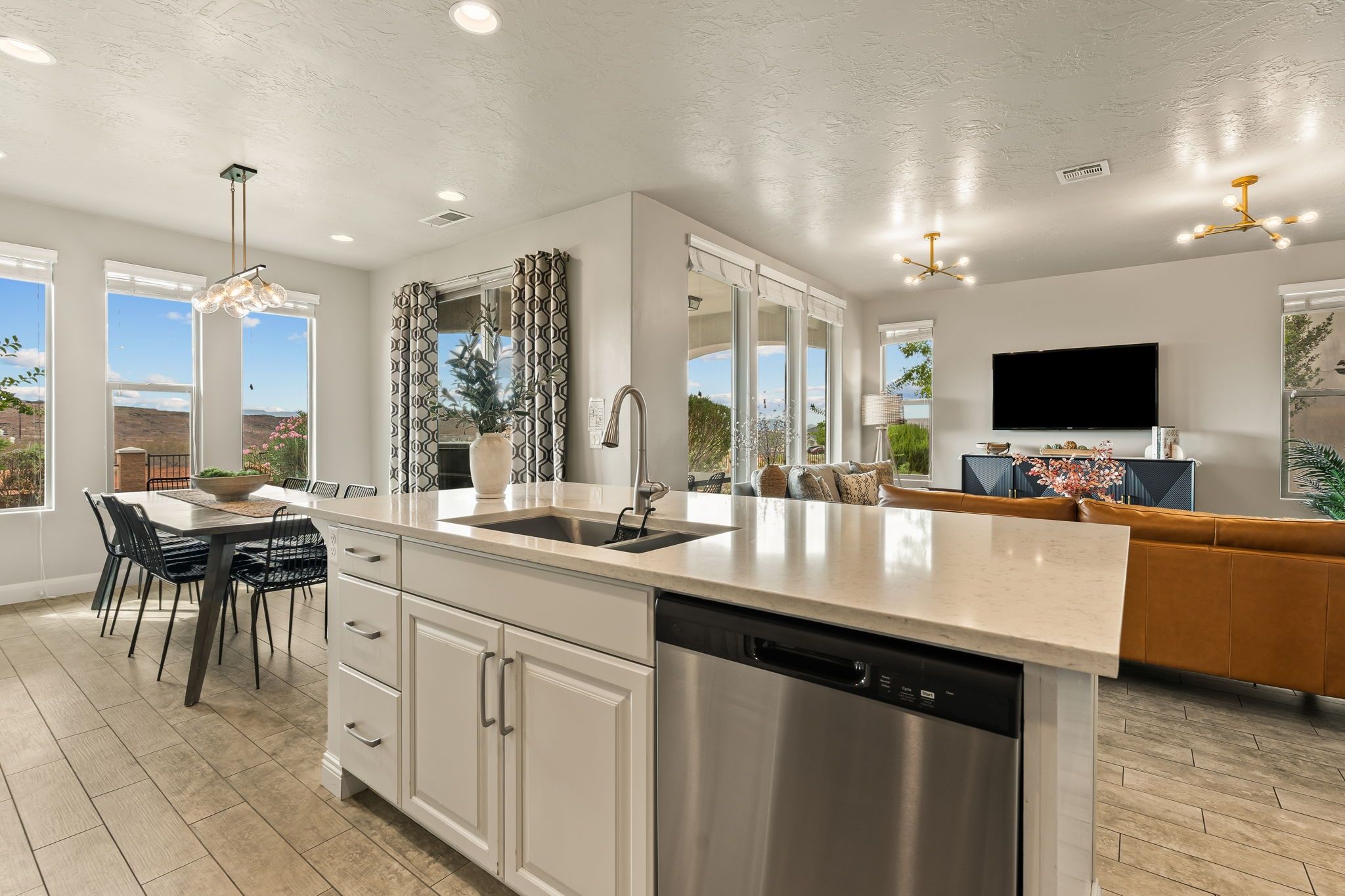 Una cocina moderna con una isla central, lavavajillas de acero inoxidable y un comedor con sillas y mesa.