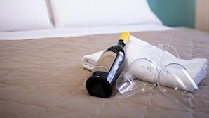 Una cama con una botella y vasos encima, un cuadro en la pared, y una pared azul.