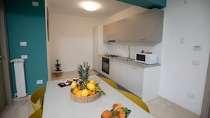 Una cocina moderna con armarios blancos, un microondas y una mesa de comedor preparada con frutas y pan.