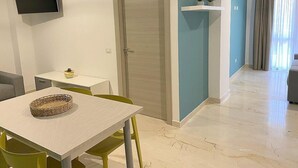 A modern living room with a dining area, a flat-screen TV mounted on the wall, and a door leading to another room. - Casa Marinara C: A modern and graceful apartment situated at a short distance from the beach, with Free WI-FI. (Balestrate)