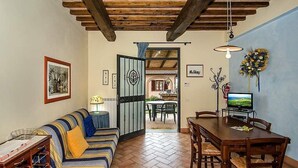 A cozy living room with a sofa, wooden dining table, and a television.