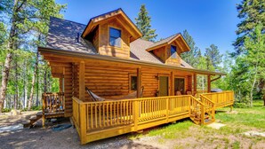 Eine Blockhütte mit Veranda, einer überdachten Terrasse und einem kleinen Sitzbereich im Freien.
