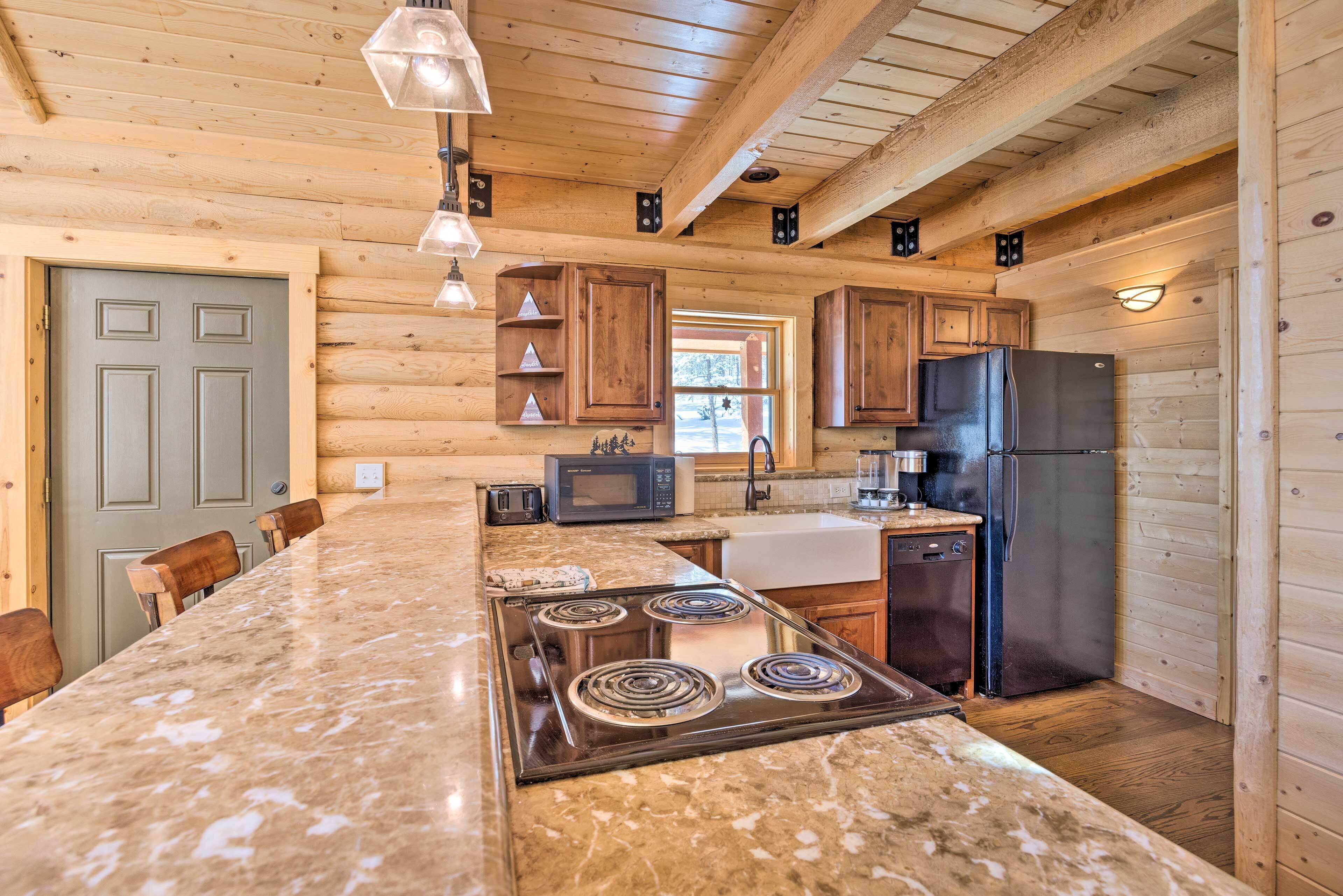 Una cocina con paredes de madera, encimera de granito, estufa, refrigerador y microondas.