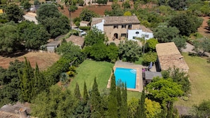 Vista aérea de una propiedad con piscina, rodeada de exuberante vegetación y edificios de piedra.