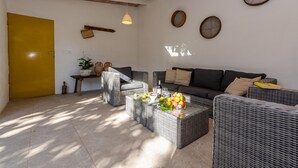 Una sala acogedora con mobiliario de mimbre, una puerta amarilla y un techo con vigas a la vista.