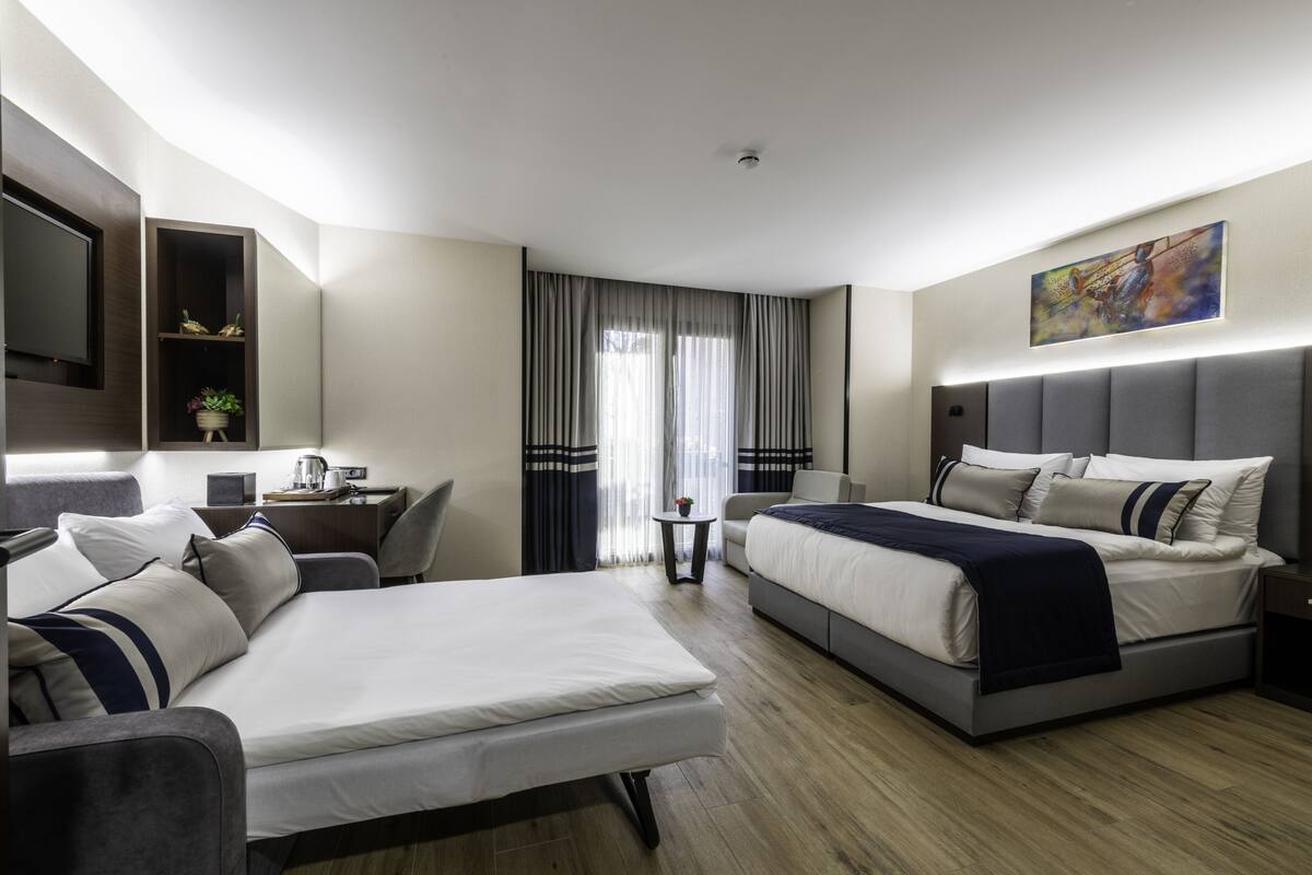 Una habitación de hotel moderna con una cama grande, un sofá, un escritorio y un televisor.