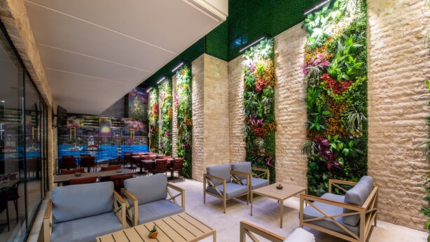 A modern outdoor seating area with wooden furniture and vertical gardens. - Aprilis Deluxe Hotel (Istanbul)