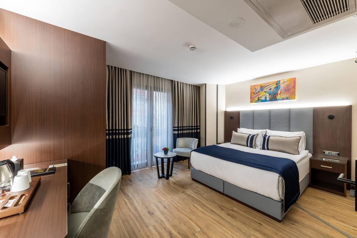 Una habitación de hotel moderna con una cama grande, un escritorio, una silla y una mesita.