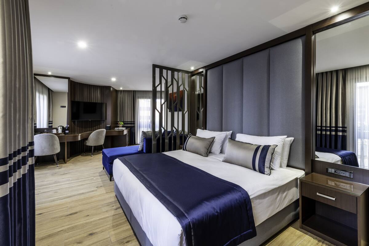 Una habitación de hotel moderna con una cama grande, un escritorio, una silla y un televisor.