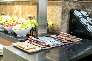 Un bufé con diversos alimentos, entre ellos ensaladas, frutas y postres.