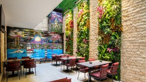 A restaurant with a mural of a cityscape and a wall adorned with vertical gardens. - Aprilis Deluxe Hotel (Istanbul)