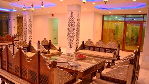 A traditional room with ornate furniture, including a sofa and a bed with intricate designs. - The Heritage Palace (Jaipur)