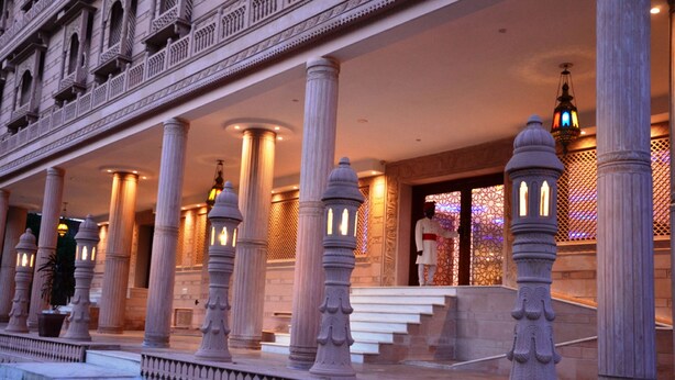 A grand entrance with ornate columns and a well-lit staircase leading to a door. - The Heritage Palace (Jaipur)