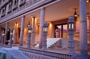 A grand entrance with ornate columns and a well-lit staircase leading to a door.
