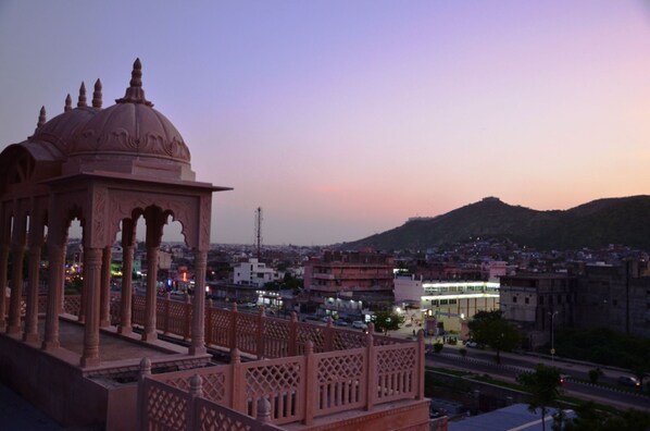 A view of a cityscape with a prominent building in the foreground and a hill in the background.
