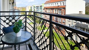 Ein Balkon mit Tisch und Stuhl, einem Blumentopf und Blick auf eine Straße mit Gebäuden.