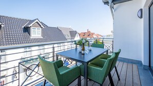 A balcony with a table and chairs, a bottle, and a glass. - Quartier Frohsinn, app. 11 (Heringsdorf)