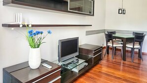 A modern living room with a flat-screen TV, a glass coffee table, a dining table with chairs, and a vase with flowers. - Matejki - Ma05 (Swinoujscie)