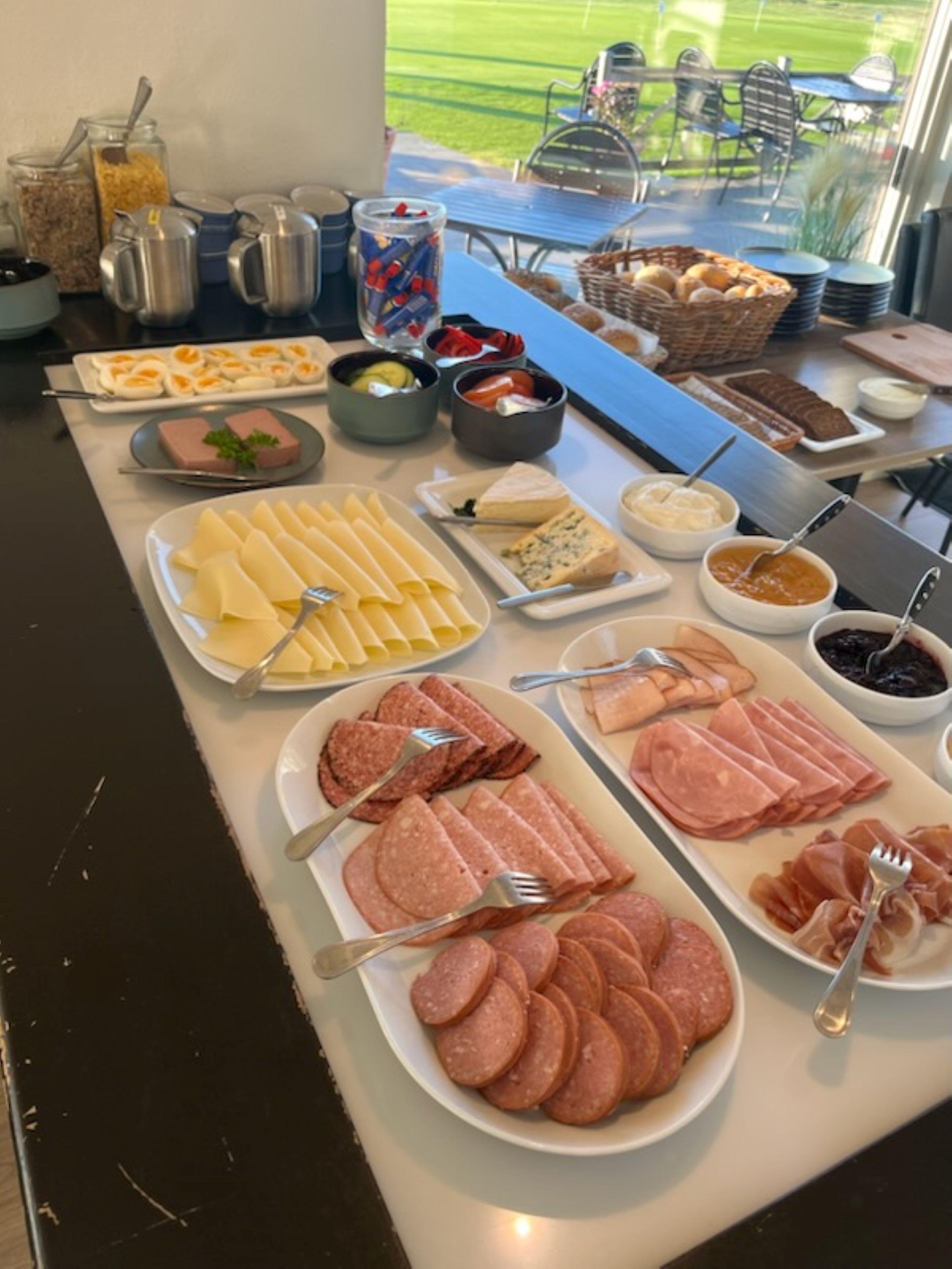 A buffet spread with various cheeses, meats, and condiments.