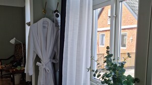 Bagno con finestra, termosifone, accappatoio appeso e pianta in vaso.