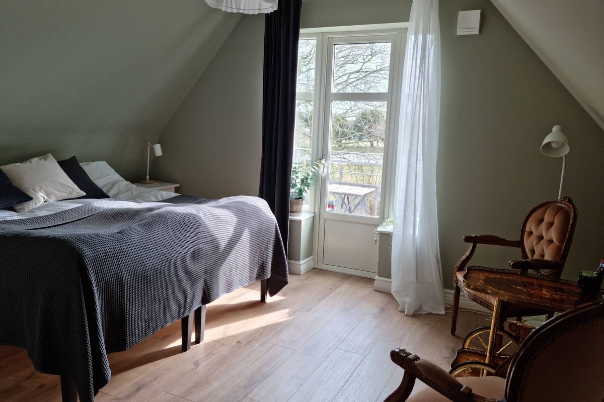 Quarto com cama, cadeira, janela e mesa.