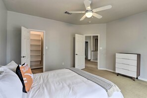 A bedroom with a bed, a ceiling fan, a wardrobe, and a door leading to another room. - Airy Villa in Austin w/ Badminton/Volleyball Court (Austin)
