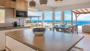Una cocina moderna con una isla grande, armarios de madera y vista al océano.