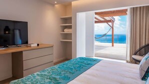 Un dormitorio con cama, televisor, escritorio y vista al mar.