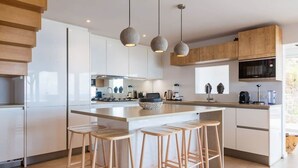 Una cocina moderna con una isla central, taburetes de madera e iluminación colgante.