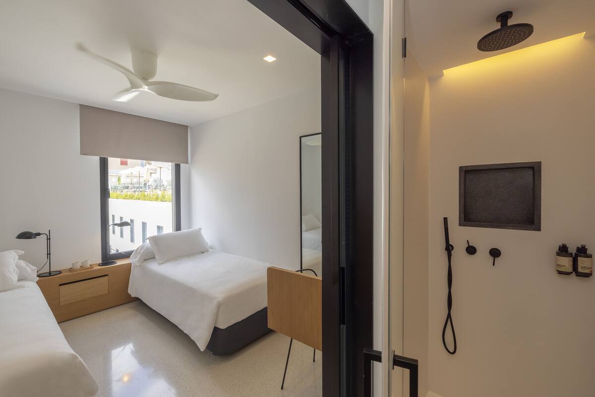 Een moderne hotelkamer met een bed, nachtkastje en een douche.