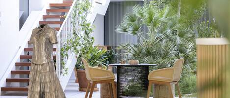 Un espace intérieur moderne comprenant un escalier, un coin repas avec des chaises en osier et des plantes en pot.