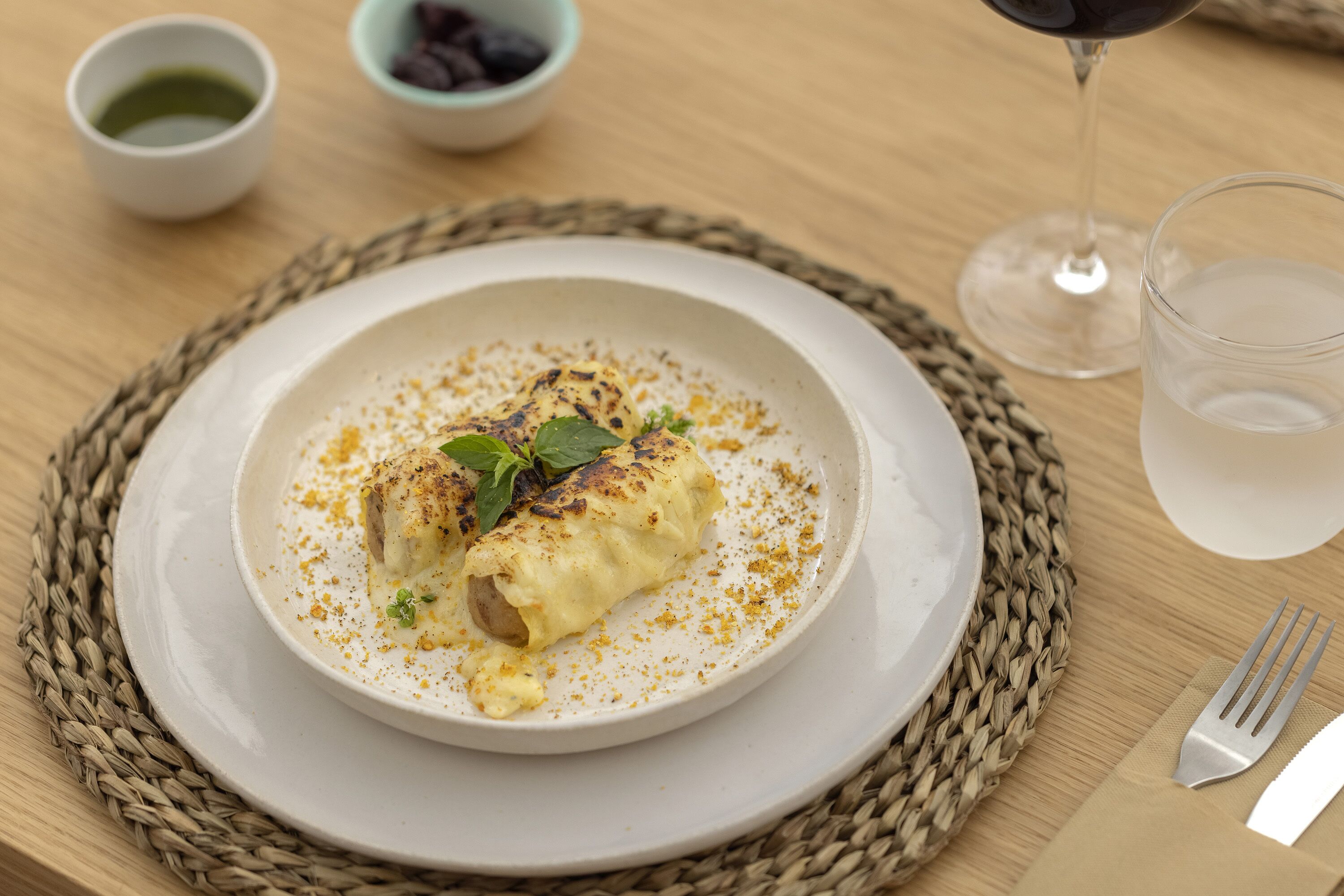 Un plato de comida con un vaso de agua y una copa de vino sobre una mesa.