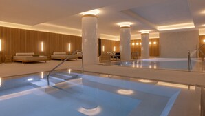 Eine moderne Hotelhalle mit einem großen Innenpool, gemütlichen Sitzbereichen und einem großzügigen Raumangebot.