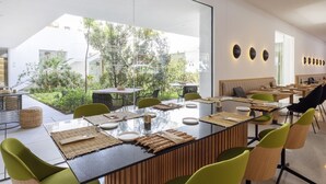 Ein moderner Essbereich mit einem langen Tisch, grünen Stühlen und Blick auf den Garten.