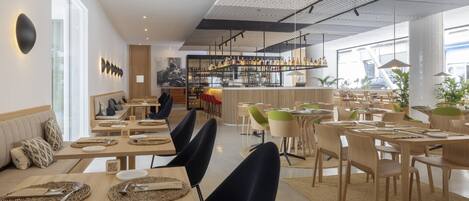 Un restaurante moderno con varias zonas de comedor, un bar y un mobiliario que incluye mesas y sillas.