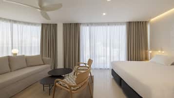 Ein modernes Hotelzimmer mit einer Couch, einem Esstisch, einem Stuhl und einem Bett.