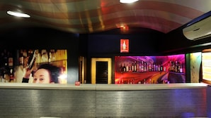 A bar area with a curved ceiling, a Coca-Cola sign, and a row of liquor bottles. - OYO Rooms Inside Udaipole (Udaipur)