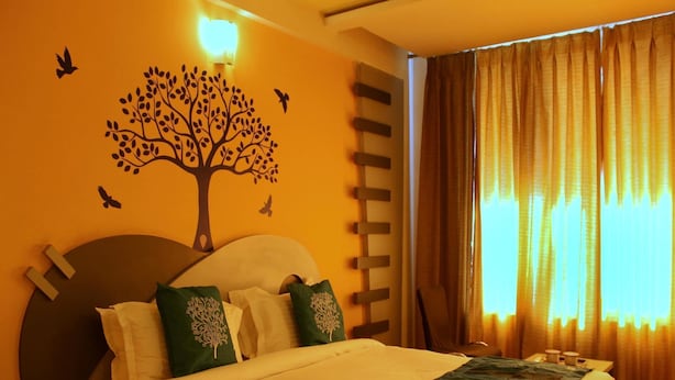 A hotel room with a bed, a wall mural of a tree, and curtains. - OYO Rooms Inside Udaipole (Udaipur)