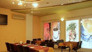 A conference room with tables set for a meeting, a ceiling fan, and a large window with a cityscape view. - OYO Rooms Inside Udaipole (Udaipur)