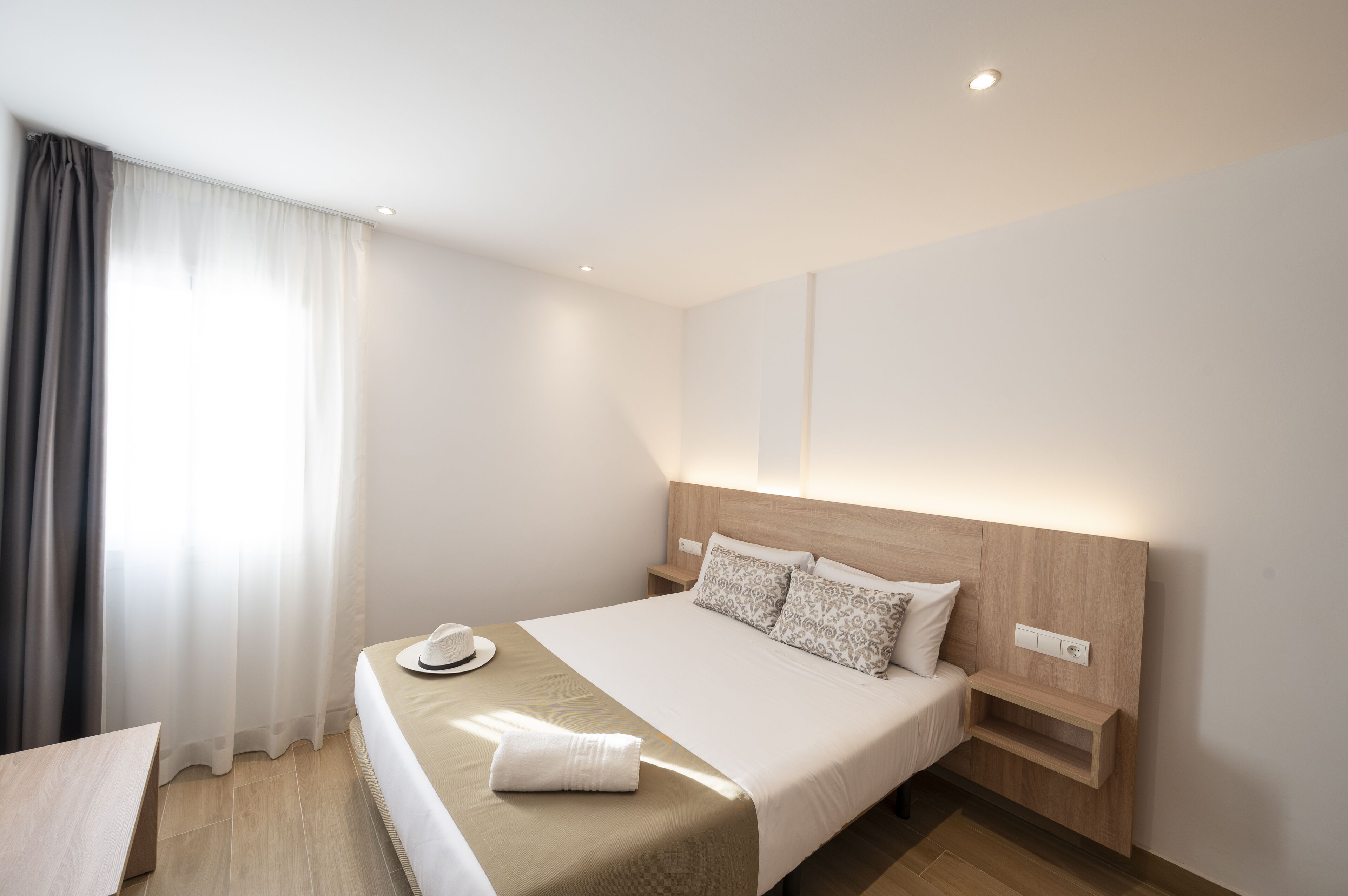 A hotel room with a bed, bedside table, and a nightstand.