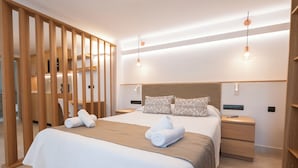 Quarto de hotel moderno com uma cama grande, divisórias de madeira, duas mesas de cabeceira e iluminação pendente.