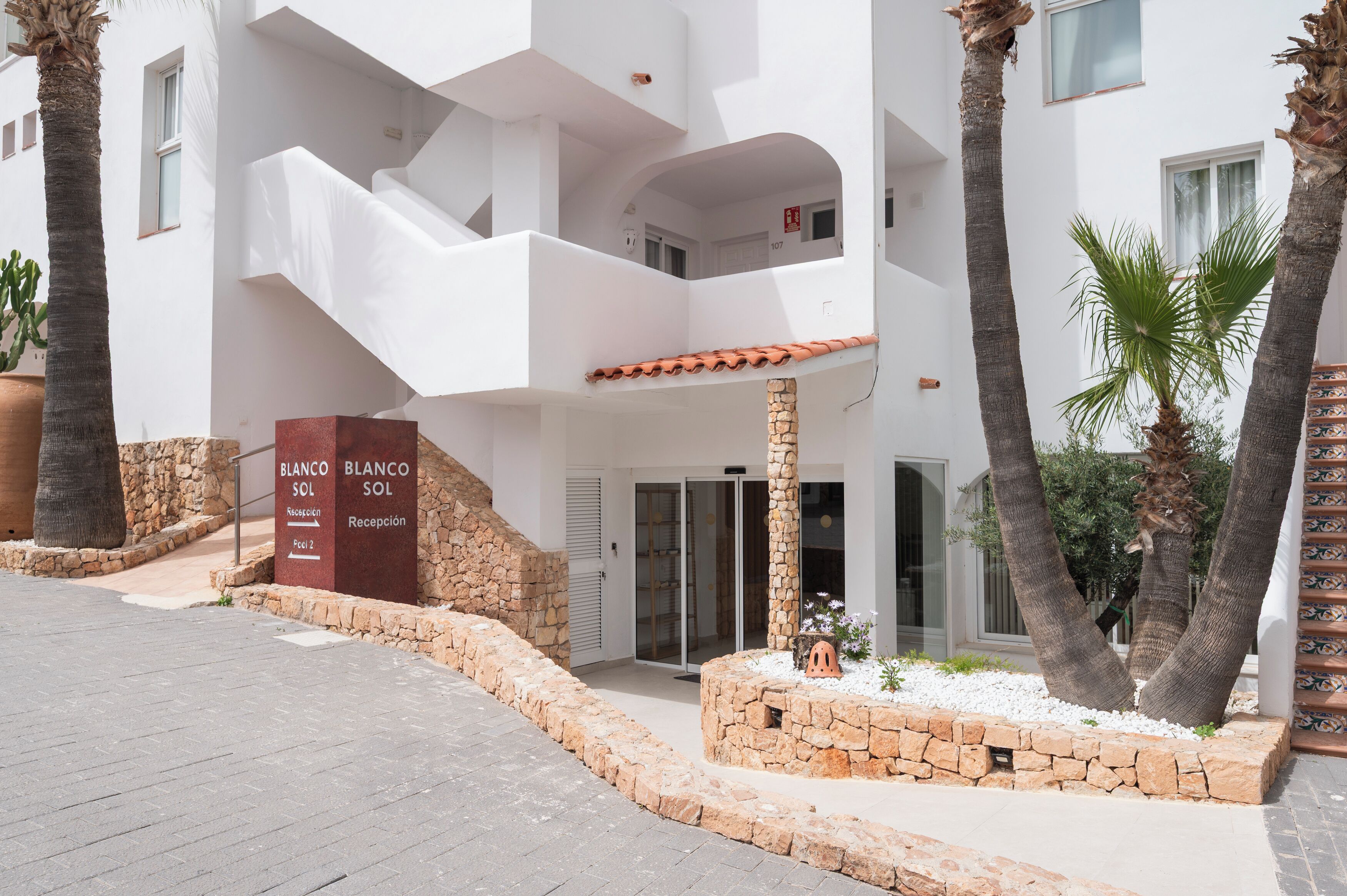 Un edificio moderno con recepción, una escalera y una pared de piedra.