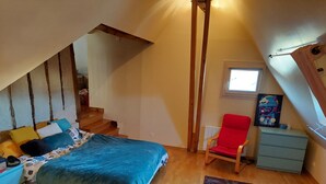 A bedroom with a bed, a red chair, a small table, a window, and a painting on the wall. - Comfortable house with swimming pool in season for 8 people close to all amenities (Amboise)
