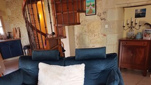 A dark blue sofa with a white throw pillow, a matching ottoman, and a wooden staircase in the background. - Comfortable house with swimming pool in season for 8 people close to all amenities (Amboise)