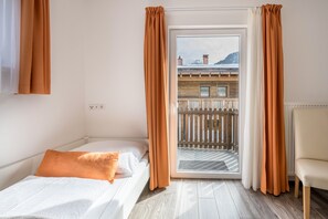 A bedroom with a bed, a chair, and a balcony with a view of buildings.