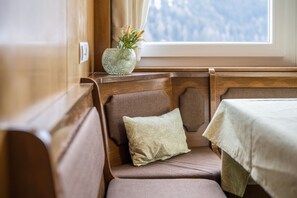 Un coin de pièce avec une fenêtre, un coussin et un vase de fleurs.