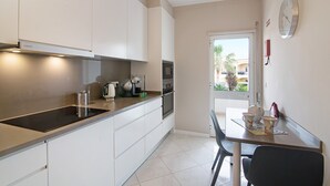 A modern kitchen with white cabinets, a black countertop, and a dining area with a table and chairs. - 'Vilamoura Apartment 3 bedroom' with Sea View, Terraces, Shared Pool & Wi-Fi (Vilamoura)