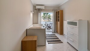 A compact kitchen with a radiator, a wooden table, a white cabinet, and a view to an outdoor balcony. - 'Vilamoura Apartment 3 bedroom' with Sea View, Terraces, Shared Pool & Wi-Fi (Vilamoura)