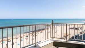 A balcony with a view of a beach and the sea.